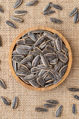Gray sunflower seeds in a wooden bowl on natural fabric, burlap. top view.