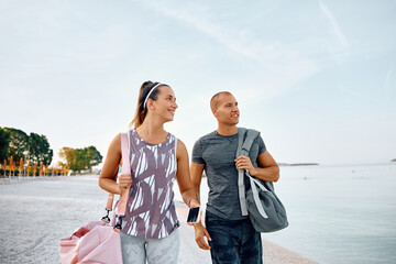 Young athletic couple taking  walk after exercising on beach.