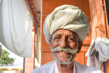 Elderly man with mustache and traditional Rajasthani turban smiling to camera