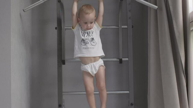 Child playing on sportive wall hanging from pull-up bar energetic and carefree nature of sports in childhood. Boy doing pull-ups on wall reflecting spirited and healthy activities lively childhood