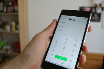 Person dialing a number on a mobile phone.