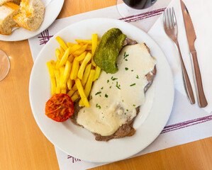 Appetizing beef steak with creamy Roquefort sauce with French fries and baked vegetables