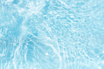 Blue water with ripples on the surface. Defocus blurred transparent blue colored clear calm water surface texture with splashes and bubbles. Water waves with shining pattern texture background.