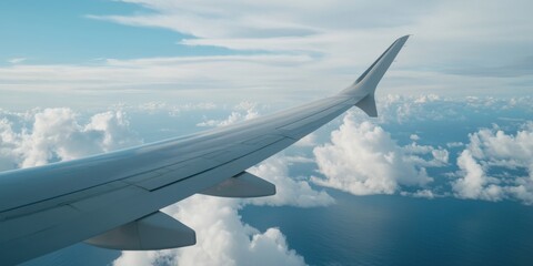 Fototapeta premium This image captures the wing of an airplane in flight, with a stunning view of the clouds and the ocean below in a serene and peaceful atmosphere.