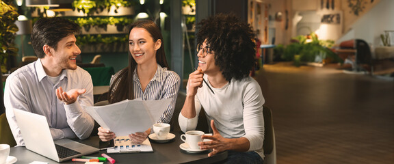 Young millennial multiethnic coworkers discussing papers during business lunch at cafe, copy space