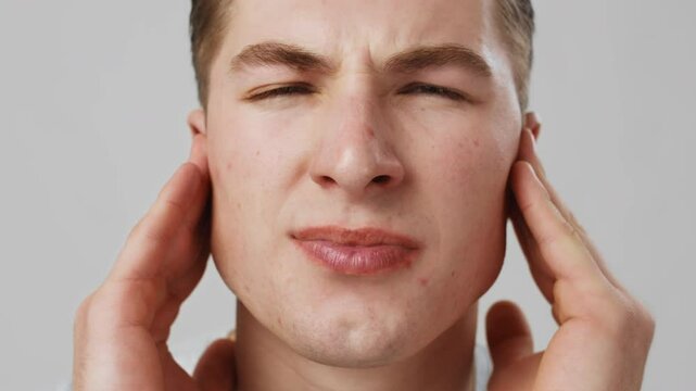 Middle ear inflammation. Close up shot of young man suffering from ear pain, shouting from ache, slow motion