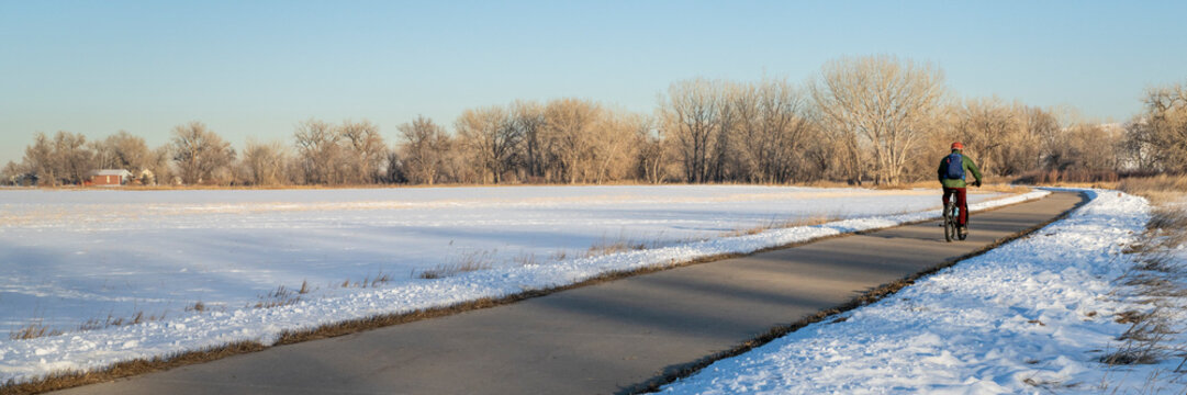 male cyclist commuting on a bike trail in winter scenery - Poudre River Trail panorama in northern Colorado