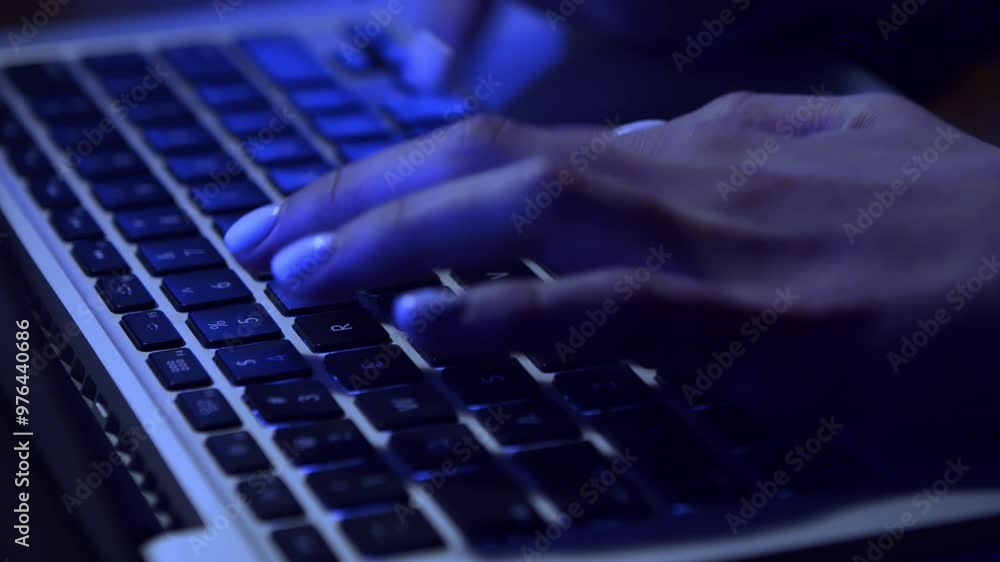 Poster A hand is engaged in typing on a laptop keyboard, illuminated by soft blue light.