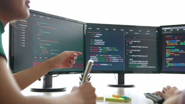 Slow motion back end software developer engineer for computer programming working together on debugging writing computing code, solving complex algorithms display on monitor in office. Burgeoning