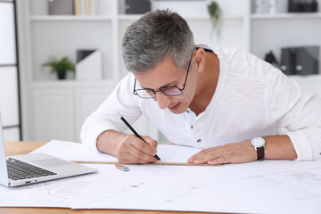 Naklejka premium Architect making engineering drawing at wooden table in office