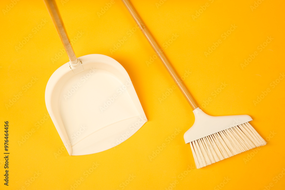 Wall mural Cleaning broom and dustpan on orange background, flat lay