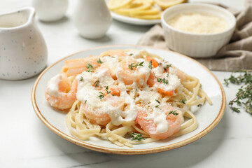 Tasty pasta with shrimps, creamy sauce and cheese on white marble table, closeup