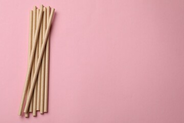 Bamboo drinking straws on pink background, top view. Space for text