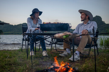 Family camping party with BBQ, and wine by the atmosphere is relaxed, capturing a moment of leisure enjoying a relaxed while sitting on folding chairs around a portable holiday camping.