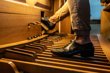 Organist's feet playing the organ pedals in a Catholic Church.