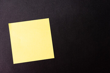Blank yellow sticky note isolated on dark background. Copy space.