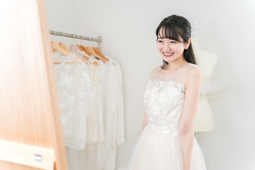 鏡を見ながら結婚式のウェディングドレスの衣装合わせ・試着をする花嫁
