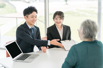 シニア女性に書類の説明をするビジネスウーマンとビジネスマン
