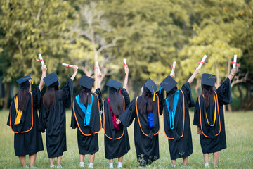 A group of women in graduation gowns are standing in a field