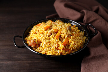 A plate with pilaf and ingredients, on a dark background.
