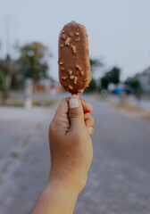 Ice cream covered with chocolate and almonds. Ice cream in the hand.