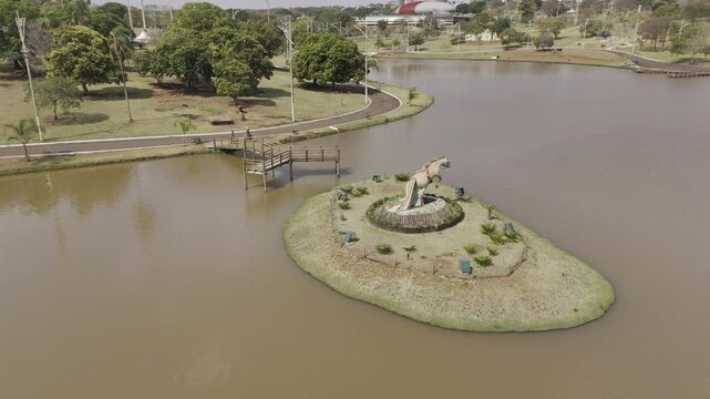 Drone orbits horse statue in middle of brown lake in Campo Grande, Mato Grosso do Sul, Brazil