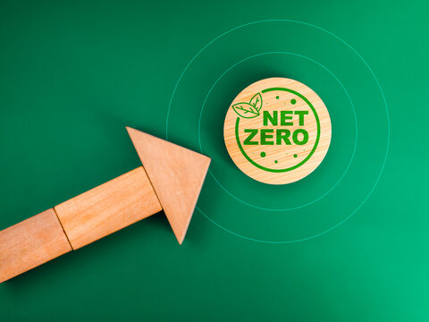 Co2 reduction, reduce carbon dioxide emissions and environment care management concept. Net zero icon on target symbol and wood blocks arrange as heading arrow on green background, minimal style.
