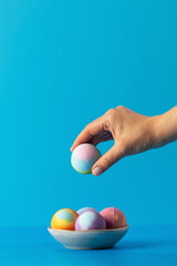 Woman takes colourful bath bomb from bowl on bathroom counter