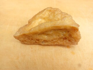 Fried tofu in triangular shape served on a cutting board.