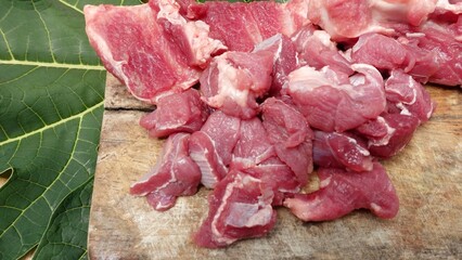 Slices of fresh beef or lamb or mutton on a chopped wood and papaya leaf base. Eid al Adha celebration concept.