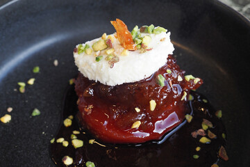 An Elegant Dessert Featuring Cream and Nuts Presented Beautifully on a Stylish Black Plate