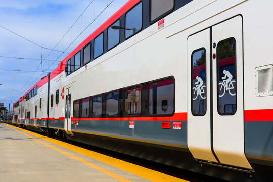 Exterior view of a Caltrain double-decker electric train Stadler KISS at a station platform, signage for bike access and emergency exits - San Jose, California, USA - September 15, 2024