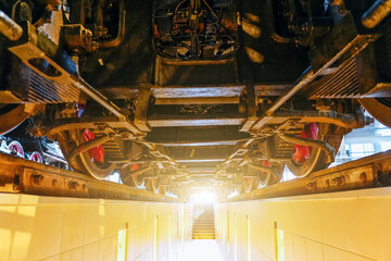 View of the engine undercarriage from the bottom of the inspection pit. Wheels of an old locomotive train locomotive from below.
