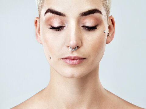 Woman, beauty and eye shadow in studio for makeup, skincare and cosmetics on white background. Female person, confidence and aesthetic for healthy skin, facial glow and self care with face piercings