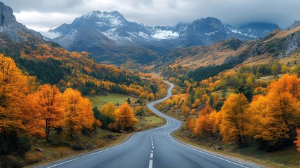 A drone photograph of a winding mountain road during autumn , with autumn foliage and dramatic landscapes
