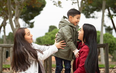 Fototapeta premium A woman is holding a child in her arms while another woman looks on