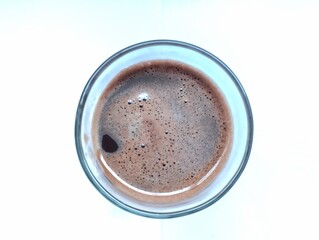 Hot chocolate drink in a transparent glass cup on a white background