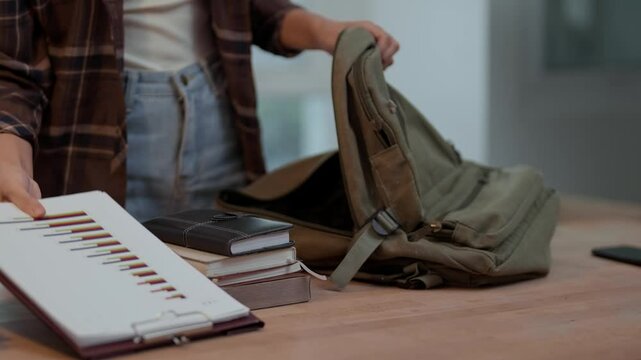 college woman putting notebook on backpack