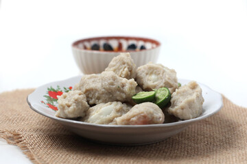 Close up of Siomay Bandung or steamed pangsit, traditional Indonesian street snack with spicy peanut sauce and soy sauce served on a white plate