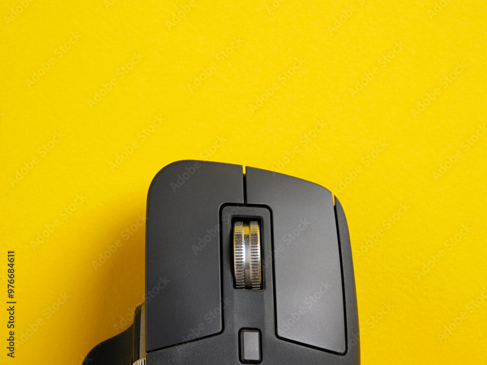 Poster black wireless computer mouse scroll wheel on yellow background.