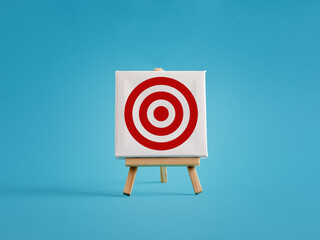 Red target on white canvas standing on easel over blue background