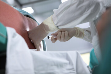 The anesthesiologist performs an epidural anesthesia on the patient's back. Injections of spinal...