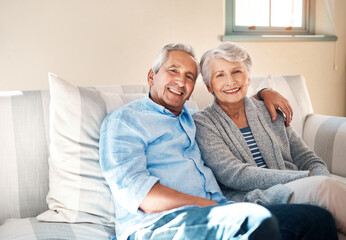 Hug, portrait and happy senior couple on sofa for connection, bonding and relaxing together at home. Smile, love and elderly man and woman hugging for resting in living room at house in Switzerland.
