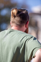 A man with a green shirt and a ponytail