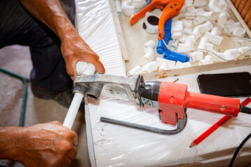 Hands of worker as holding plastic water pipes in device for melting, welding