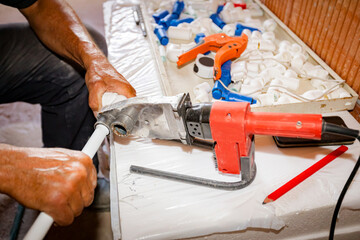 Hands of worker as holding plastic water pipes in device for melting, welding