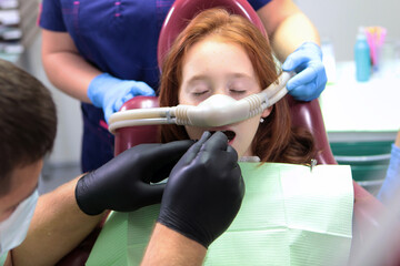 A little girl is being treated for teeth with anesthesia. The girl closed her eyes. Nitrous oxide...