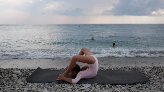 Teenager girl practice gymnastic and stretching exercise. Child girl practicing yoga at sea, seaside. Leg-split