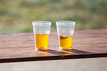 Two plastic cups of beer on a wooden table