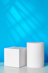 White geometric shapes on a clean surface against a bright blue background with soft shadows